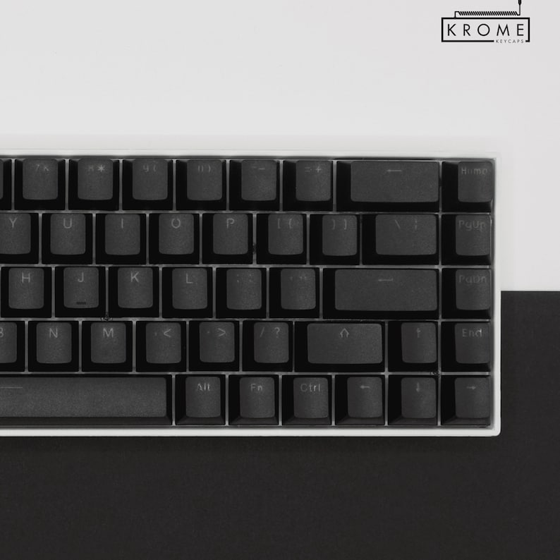 May include: A black mechanical keyboard with white keycaps and a white frame. The keyboard has a standard layout with function keys, arrow keys, and a number pad. The keyboard is on a white surface.