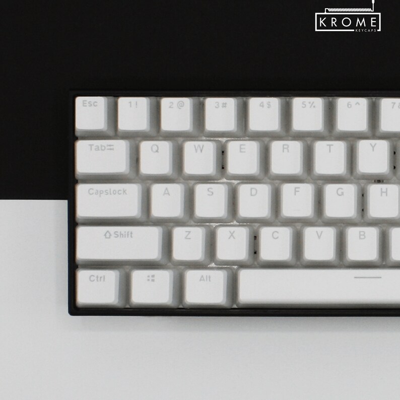 May include: A white mechanical keyboard with black keys and a black frame. The keys have white lettering and symbols. The keyboard has a row of function keys, a row of number keys, a row of letter keys, a row of punctuation keys, and a row of arrow keys. The keyboard also has a space bar, a backspace key, a tab key, a caps lock key, a shift key, a control key, and an alt key.