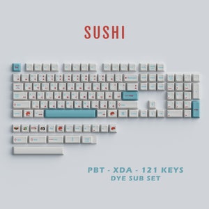 Könnte beinhalten: Eine weiße Tastatur mit einem blauen und roten Tastenset. Die Tastenkappen zeigen Sushi-Designs. Die Tastatur ist mit "PBT - XDA - 121 KEYS DYE SUB SET" beschriftet.