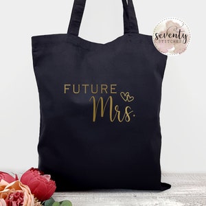 May include: Black tote bag with gold text that says "FUTURE Mrs." with two gold hearts above the text.