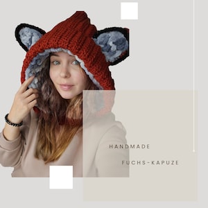 Könnte beinhalten: Handgefertigte rote Fuchs-Kapuze mit grauem Fellfutter und Ohren. Die Kapuze ist gehäkelt und hat eine flauschige Textur.