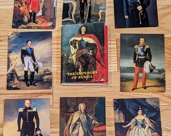 May include: A collection of vintage postcards featuring portraits of Russian emperors. The postcards are arranged in a grid pattern on a wooden surface. The postcards are in various colors and feature different emperors in their royal attire. The text "The Emperors of Russia" is printed on one of the postcards.