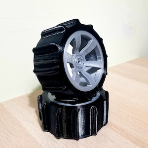 May include: Two black 3D printed wheels with a silver rim. The wheels have a textured tread pattern.