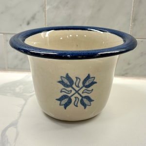 May include: A small, white ceramic planter with a blue rim and a blue and white tulip design.