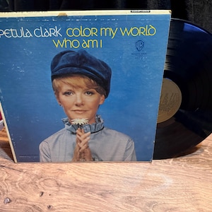 Peut inclure: Album vinyle vintage de Petula Clark, intitulé "Color My World" et "Who Am I", avec un portrait de l'artiste sur fond bleu. Le disque est noir, avec le logo Warner Bros. Records.