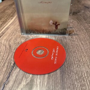 May include: A CD case with the text "CHERIE CALL" and "Heart Made of Wind" on the cover. A red CD is in front of the case, with the same text printed on it. The case is clear plastic, and the CD is red.
