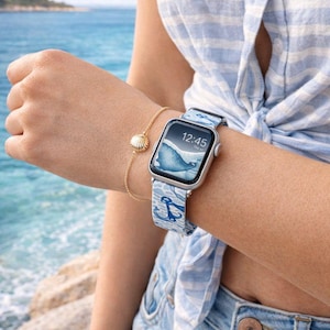 May include: A silver smartwatch with a blue and white nautical-themed strap featuring anchor designs. The watch shows the time as 12:45. A gold bracelet with a seashell pendant is also visible. The overall theme is nautical and beach-inspired.
