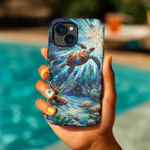 May include: A smartphone case featuring a stained-glass style design of a sea turtle swimming underwater. The case has a blue, green, and brown color scheme with a sunburst effect in the background. The case is held in a hand with yellow nail polish.