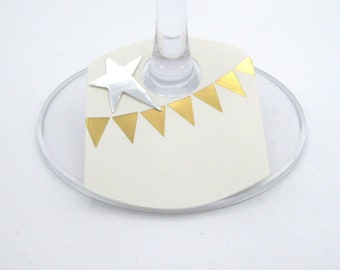 May include: A white wine glass with a gold and silver decorative tag. The tag has a silver star and a gold banner of triangles.