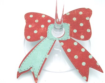 May include: Red and white polka dot bow with a light blue ribbon, designed to be placed around the stem of a wine glass.