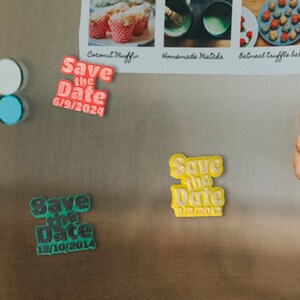 May include: Three refrigerator magnets with the text "Save the Date" and different dates. The magnets are in green, yellow, and pink.
