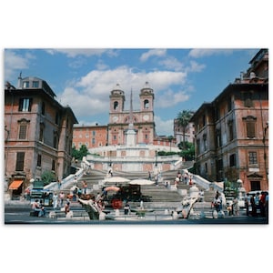 May include: A wide shot of the Spanish Steps in Rome, Italy. The steps are made of stone and are lined with trees and buildings. There are people walking up and down the steps.