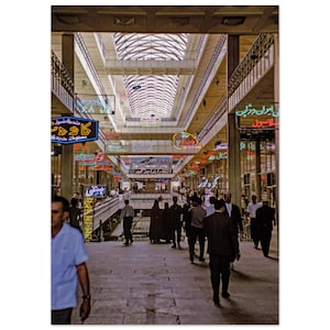 May include: A vintage photograph of a busy marketplace with a high, arched ceiling and multiple levels. Neon signs in various languages are suspended from the ceiling. People are walking along the stone pathway. The image has a retro feel.