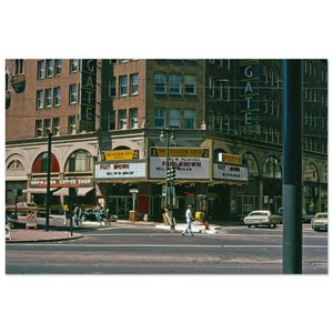 Op de afbeelding: Een vintage foto van het Golden Gate Theatre in Los Angeles, Californië. De marquee geeft "RKO Golden Gate 2" en "Now Playing Foxy Brown" aan. Het theater bevindt zich op een drukke straathoek met een Hav-A-Java Coffee Shop ernaast.