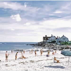 May include: A vintage photograph of a beach scene with people enjoying a sunny day. The image shows a sandy beach, blue ocean, and a cloudy sky. Several people are on the beach, some with umbrellas.