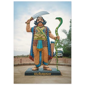 May include: A colorful statue of a figure holding a large curved sword and a green snake. The figure is dressed in ornate clothing with blue, gold, and orange hues. The statue is on a black base with text in a foreign language.