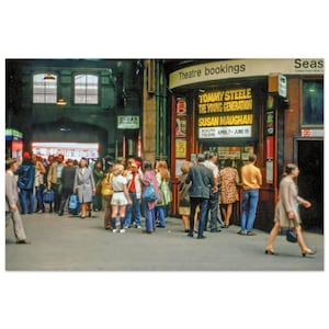 May include: A vintage photograph of a bustling train station scene. A ticket booth with the text "TOMMY STEELE THE YOUNG GENERATION SUSAN MAUGHAN" is surrounded by people. The image captures the atmosphere of a busy public space.