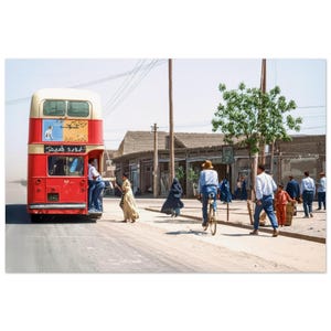 May include: A vintage double-decker bus, painted red and cream, is the focal point of a street scene. People are seen entering and exiting the bus. Other people are walking and riding bicycles on the street. Buildings line the street.