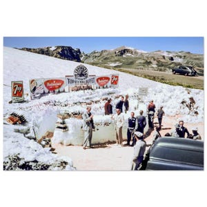 Puede incluir: Fotografía vintage de una escena de montaña nevada con un buffet. Se ven letreros de Budweiser y 7 Up. Un grupo de personas se reúne alrededor del buffet, con un coche aparcado cerca. El letrero dice "Top of the World Buffet".