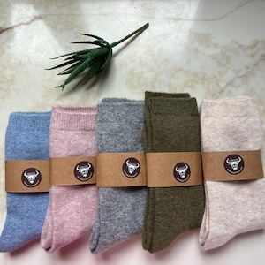 May include: Five pairs of crew socks in blue, pink, gray, olive green, and cream. Each pair is wrapped in a brown paper band featuring a circular logo with a bull illustration and the text Tennessee Deep Draw Yak Ranch.