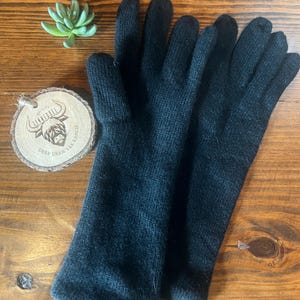 May include: A pair of black knit gloves. The gloves are long and extend past the wrist.