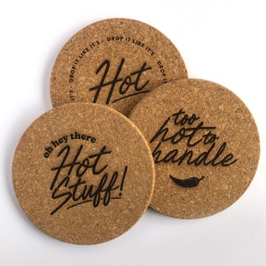 May include: Three round cork coasters with black text. The first coaster says "Drop it like it's Hot". The second coaster says "Oh hey there Hot stuff!" The third coaster says "Too hot to handle" with a red chilli pepper graphic.