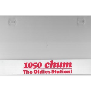 May include: White sign with red text that reads "1050 chum The Oldies Station!"