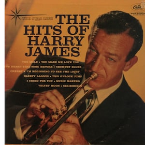 May include: A vintage vinyl record cover featuring a black and white photo of Harry James playing a trumpet. The cover is yellowed with age and has the text "The Hits of Harry James" in large, bold letters. The album includes songs like "The Mole", "You Made Me Love You", "I've Heard That Song Before", "Trumpet Blues", "Cherry", "I'm Beginning to See the Light", "Sleepy Lagoon", "Two O'Clock Jump", "I Cried for You", "Music Makers", "Velvet Moon", and "Ciribiribin".