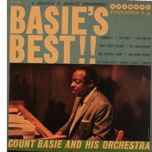 Puede incluir: Una portada de disco de vinilo azul y amarilla con el texto "Basie's Best!" en letras grandes y en negrita. La portada presenta una foto en blanco y negro de Count Basie tocando el piano. El texto "Count Basie and His Orchestra" está impreso en la parte inferior de la portada.
