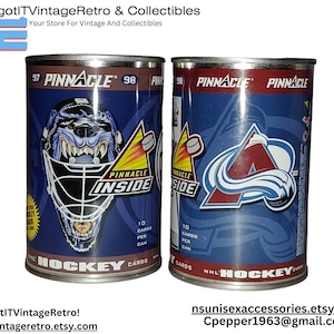 May include: Two vintage Pinnacle NHL Hockey Cards tins. One tin features a goalie mask graphic with the text "INSIDE". The other tin displays a team logo. Both tins are blue and silver with the text "NHL HOCKEY CARDS".