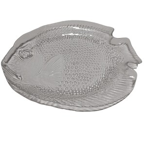 May include: A clear glass serving dish shaped like a fish. The dish has a textured surface and a raised design of a fish.