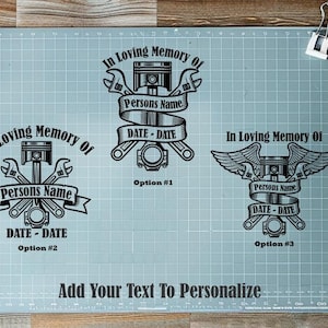 May include: A light blue cutting mat displays three memorial designs with engine-themed graphics. Each design includes the text "In Loving Memory Of," space for a name, and a date. The phrase "Add Your Text To Personalize" is at the bottom.