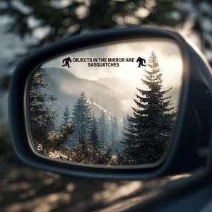 May include: A car side mirror with the text "OBJECTS IN THE MIRROR ARE SASQUATCHES" and a silhouette of a Bigfoot. The mirror reflects a mountain landscape with evergreen trees and a bright sky.