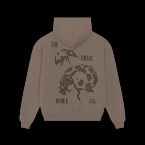 May include: A taupe-coloured hooded sweatshirt featuring a dark brown graphic of two ladybugs on the back. The text "THE GREAT" is printed above the insects, while "DIVIDE" and "NOAH KAHAN" are printed below in a dark brown, distressed font.
