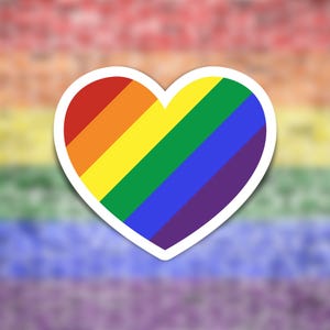May include: A heart-shaped sticker with a rainbow design, featuring red, orange, yellow, green, blue, and purple stripes. The sticker has a white border and is set against a blurred rainbow background.