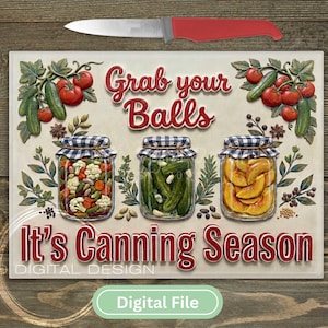 May include: A decorative sign with the text "Grab your Balls, It's Canning Season" and three jars filled with vegetables and fruit. A knife with a red handle is above the sign. The sign has a digital file label.