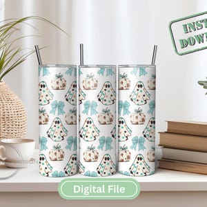 May include: Three white tumblers with a pattern of ghosts and pumpkins in shades of green and brown. The tumblers are on a white surface with a wooden table and a green plant in the background.