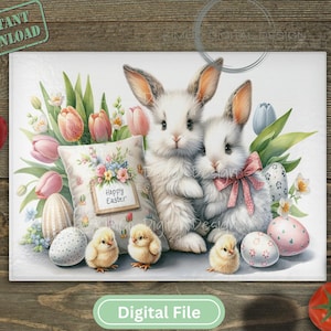 Puede incluir: Dos conejos blancos con lazos rosas se sientan en una cesta de huevos de Pascua de color rosa pastel y azul. Los conejos están rodeados de flores de primavera y una almohada con las palabras "Feliz Pascua" en ella.