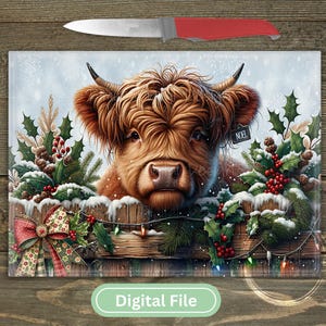 May include: A rectangular glass cutting board featuring a brown Highland cow with horns, surrounded by holly, pine branches, and red berries on a wooden fence. A red-handled knife rests above the board, which displays the text NOEL.