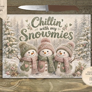 May include: A digital graphic featuring three snowmen wearing knit hats and scarves in shades of sage green and dusty pink. The text reads Chillin' with my Snowmies. The background shows a snowy forest with pine trees and small heart accents.