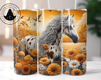 May include: A tumbler featuring a white and brown horse with a flowing mane, set against a warm, golden landscape with sunflowers, daisies, and birds. The tumbler has the text "CLOAK AND DAGGER CREATIONS" in a circular logo.