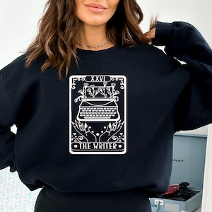 May include: Black sweatshirt with a white graphic of a typewriter with flowers and the text "XXVI THE WRITER".