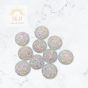 Peut inclure: Dix cabochons ronds blancs irisés avec une finition scintillante. Les cabochons mesurent environ 2,5 cm de diamètre.