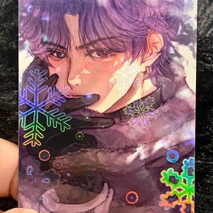May include: A holographic trading card with an anime-style illustration of a person with purple hair and a black outfit. The card has snowflake and circle accents. The person is wearing black gloves and has a serious expression.