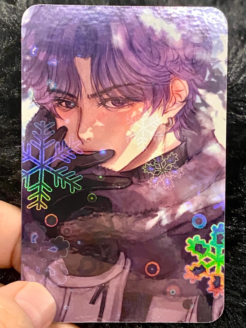 May include: A holographic trading card with an anime-style illustration of a person with purple hair and a black outfit. The card has snowflake and circle accents. The person is wearing black gloves and has a serious expression.
