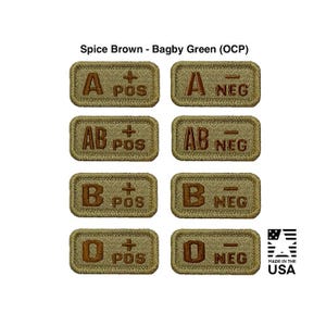 Könnte beinhalten: Acht gestickte Aufnäher in Braun- und Grüntönen, die jeweils eine Blutgruppe (A, AB, B, O) mit positiven oder negativen Symbolen zeigen. Der Text "MADE IN THE USA" ist ebenfalls sichtbar. Die Aufnäher sind rechteckig.