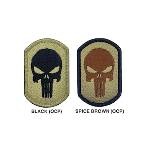 Könnte beinhalten: Zwei gestickte Patches mit einem Schädelmotiv. Die Patches sind in einem Tan-Ton mit schwarzen und braunen Schädeln. Der Text unter den Patches lautet "BLACK (OCP)" und "SPICE BROWN (OCP)".