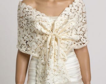 Può includere: Sciarpa in pizzo color avorio con un delicato motivo floreale, annodata sul davanti. La sciarpa è drappeggiata su un abito bianco, creando un look elegante e romantico. Il design a spalle scoperte aggiunge un tocco di raffinatezza. Perfetta per matrimoni.