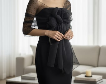 May include: A black formal dress with a large bow detail at the bodice. A sheer, black, polka-dot shawl is draped over the shoulders. The dress is a classic, elegant style, suitable for evening wear or special occasions.