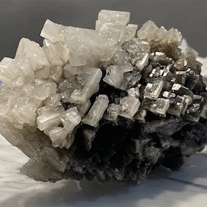 May include: A cluster of salt crystals, some white and some dark grey, forming a unique and interesting rock formation.